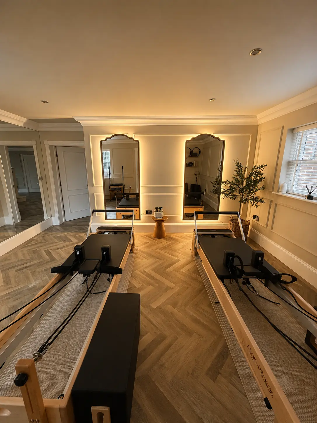 Two reformers facing the illuminated mirrors inside Rewind Pilates in Poole